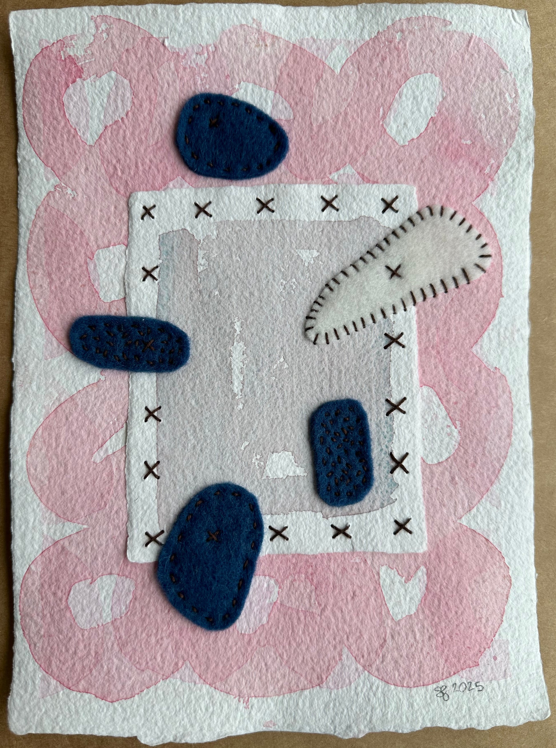 A piece of paper art featuring felt and thread in blue and white colors on a pink background with black X marks and heart shapes by Suzanne Gibbs.