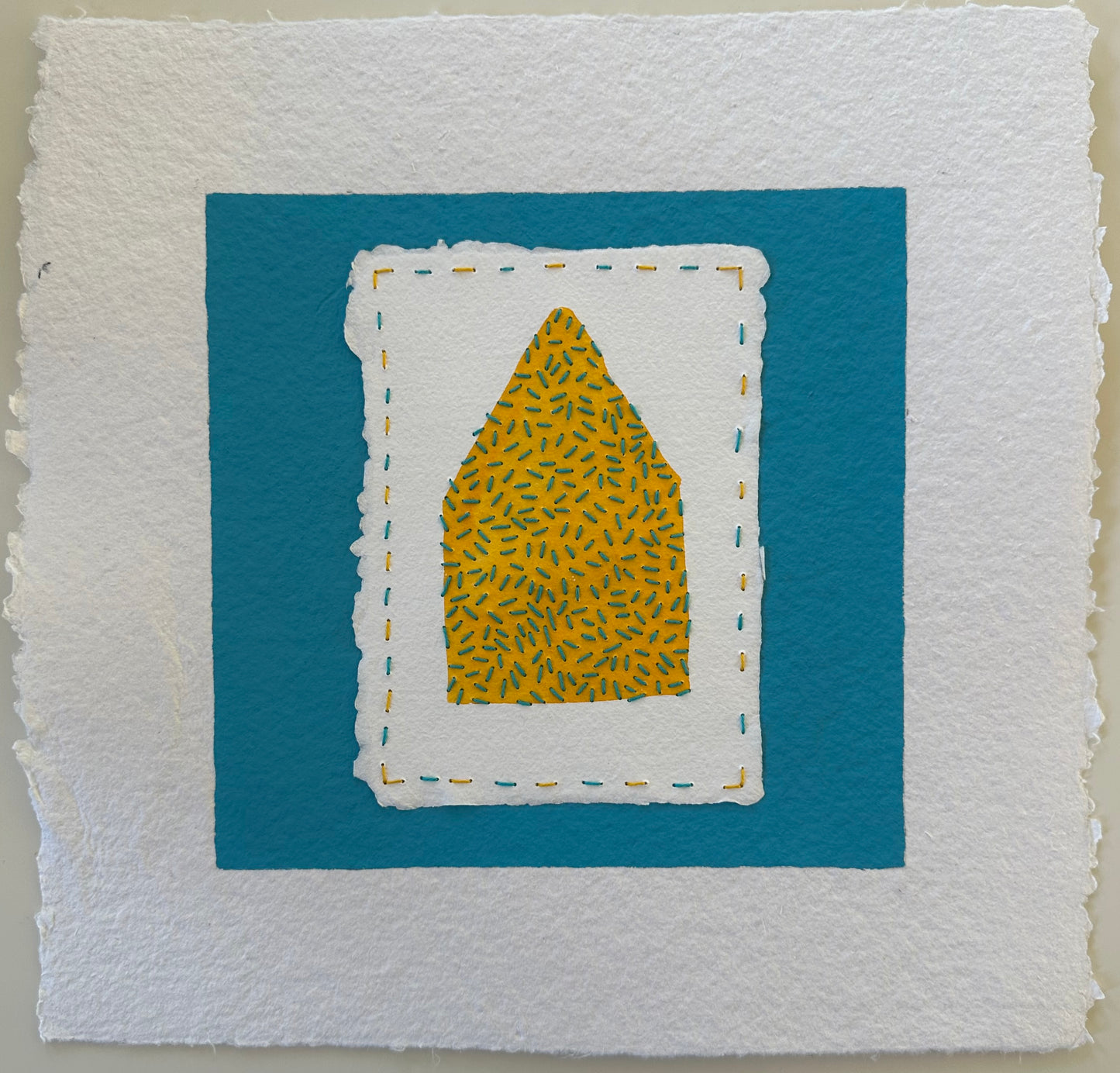 Fragments of Home #38, Not So Seedy by Suzanne Gibbs. A yellow house shape filled with teal stitches, layered on white paper and set against a teal ground.