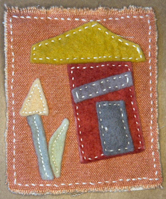 Textile artwork by Suzanne Gibbs from her Fragments of Home series, featuring a red house with a golden roof and an abstract flower on a cinnamon-colored fabric background.