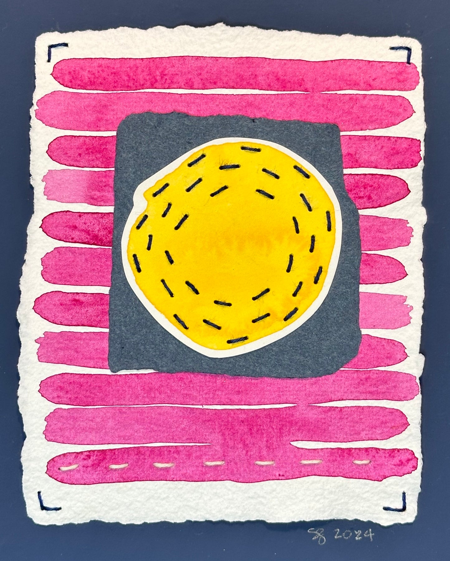 A piece of abstract art featuring a stitched quilted texture in pink, blue, and yellow colors, signed on the front by Suzanne Gibbs.