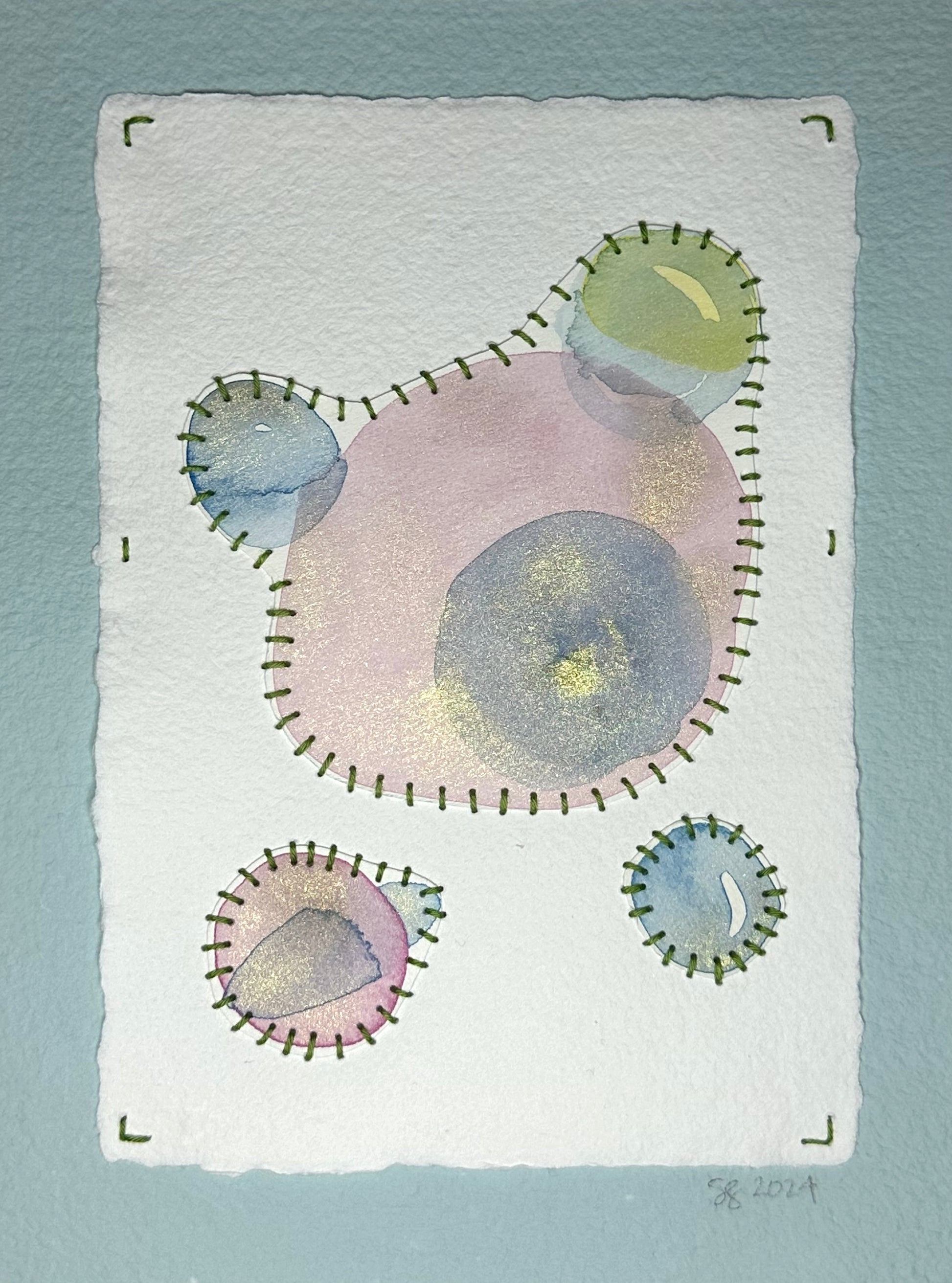 A watercolor, sashiko thread art piece on paper with a minimalist abstract design in muted pinks and blues, signed and dated by the artist, Suzanne Gibbs on the front.