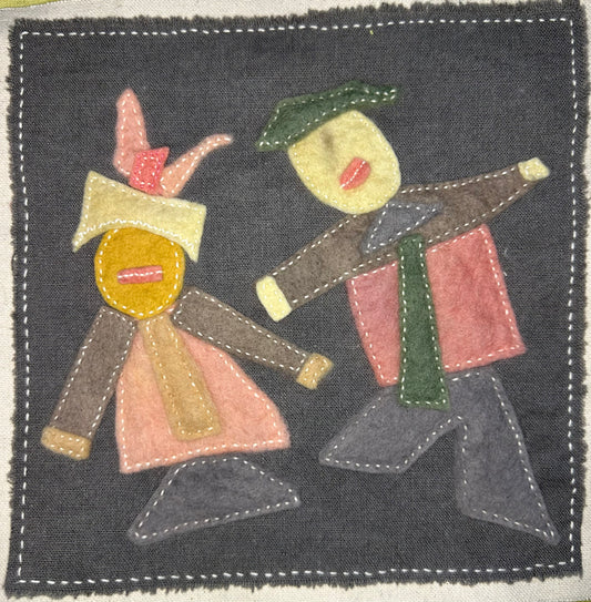 Fragments of Home textile art by Suzanne Gibbs with two abstract felt figures in pink, brown, green, and yellow on a dark gray fabric background, hand-stitched in white.