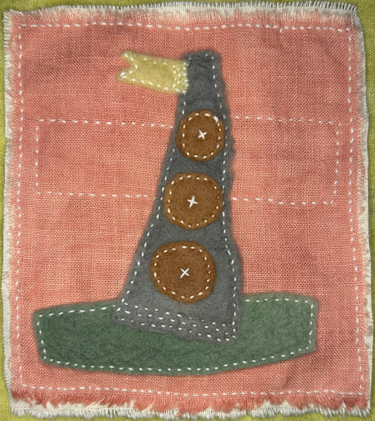 Fragments of Home textile art by Suzanne Gibbs with felt shapes in gray, brown, green, and yellow on pink fabric, hand-stitched to suggest a whimsical house boat.