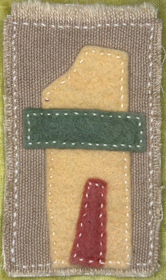 Fragments of Home textile art by Suzanne Gibbs with a yellow felt house shape, green band, and red doorway on a tan background, hand-stitched in white.
