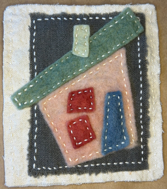 Textile artwork by Suzanne Gibbs from her Fragments of Home series, featuring a pink house with a green roof on a grey background