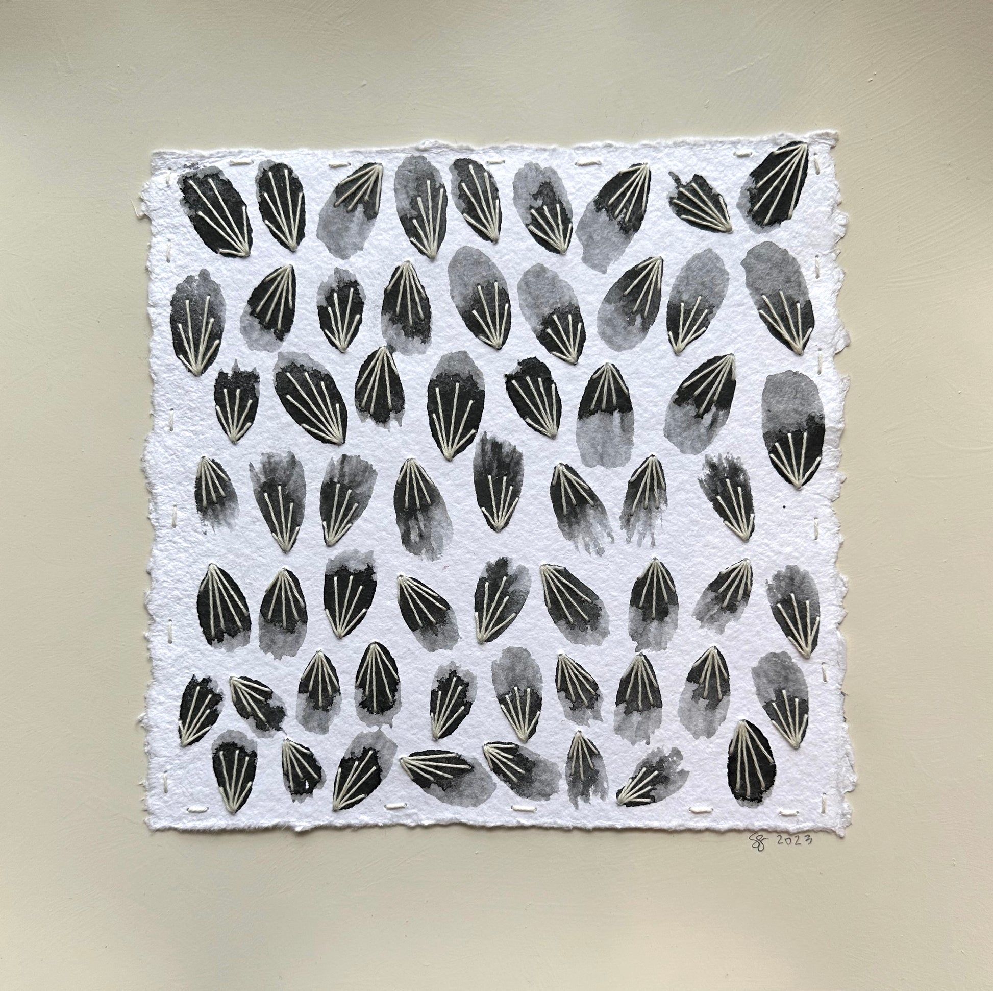 A collage painting featuring a regular pattern of black petal shapes on a white background, executed with watercolor and thread by Suzanne Gibbs.